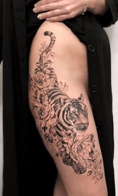 a woman's thigh with a tiger and flowers tattoo on her leg, while the lower half is covered in black ink