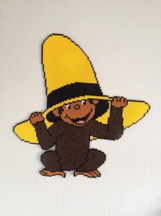 a monkey wearing a yellow hat with a banana on it's back and arms