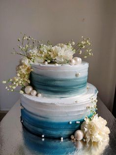 a three tiered blue and white cake with flowers on top