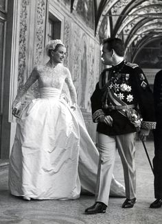 a black and white photo of a woman in a wedding dress standing next to a man