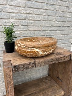 a large loaf of bread sitting on top of a wooden table next to a potted plant