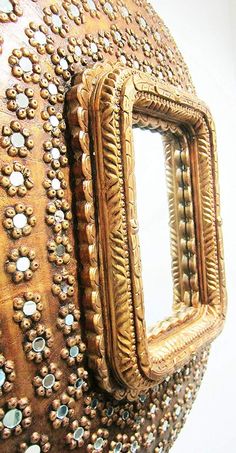 an ornately decorated mirror is shown in the shape of a vase with beads on it