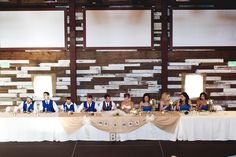 a group of people sitting at a table in front of a wall with wooden planks