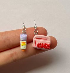 a hand holding two small earrings with the word boo on it and a candy bar