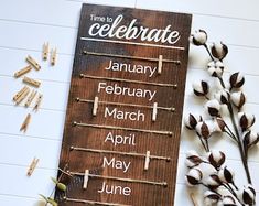 a wooden sign sitting on top of a table next to some cotton flowers and clothes pins