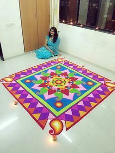 a woman sitting on the floor in front of a brightly colored carpet with lights around it