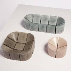 three pieces of stone sitting on top of a white table next to each other in different colors