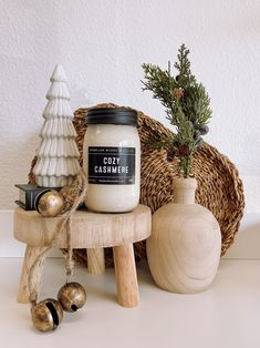 a white candle sitting on top of a wooden stool next to a vase and christmas decorations