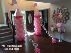 pink balloons are chained to chains in front of a door and stairs with mirrors on the wall