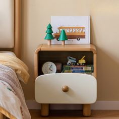 a nightstand with a clock and toy cars on it next to a small child's bed