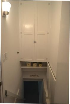 an empty room with white cupboards and blue carpeted stairs leading up to the door