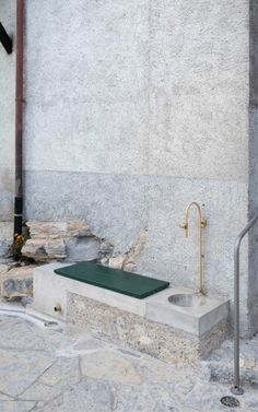 a concrete bench sitting next to a wall with a metal hand rail on the side