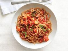 a white bowl filled with pasta covered in tomato sauce and garnished with basil