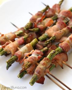 asparagus and bacon skewers on a white plate