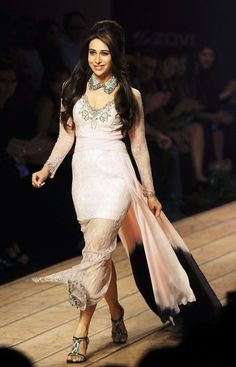 a woman walking down a runway in a white dress