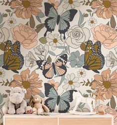 a teddy bear sitting on top of a dresser next to a wallpaper with butterflies and flowers