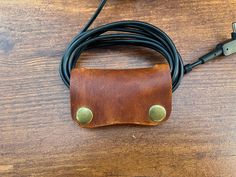 a leather case sitting on top of a wooden table next to a charger and cable