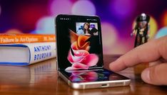 a cell phone sitting on top of a wooden table next to a book and pen