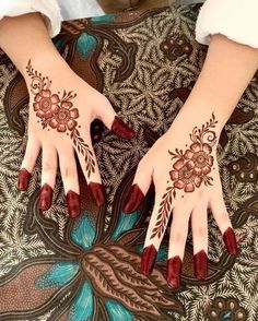 woman's hands with hennap and flowers painted on their palms, sitting on the ground