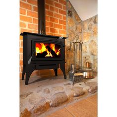 a wood burning stove sitting in front of a brick wall next to a stone floor