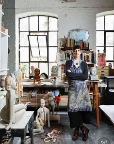 a woman standing in an art studio with her arms crossed