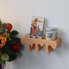 there is a shelf with some books on it next to flowers and a candle holder