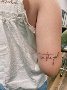 a woman with a tattoo on her arm that says see the good in cursive writing