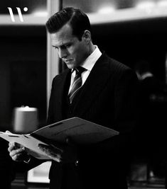 a man in a suit and tie holding a binder while looking at something on a clipboard