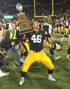 a football player holding up a trophy on the field