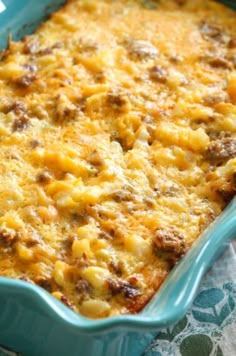 a casserole dish with meat and cheese in it sitting on a tablecloth