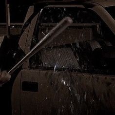 a man is washing his car with a high pressure sprayer in the rain at night