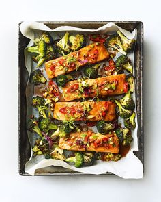 salmon, broccoli and other vegetables on a baking sheet with parchment paper in it