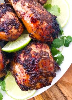 grilled chicken with limes and cilantro on a white plate next to a wooden table