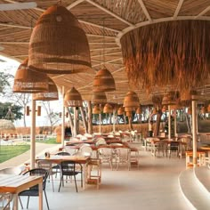 an outdoor dining area with tables, chairs and straw umbrellas hanging from the ceiling