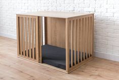 a dog crate sitting on top of a hard wood floor next to a white brick wall