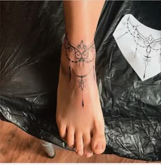 a woman's foot with a tattoo on it and a piece of paper in the background