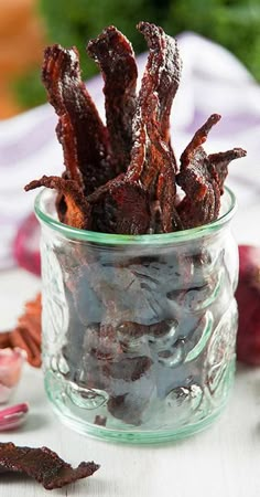 a glass jar filled with bacon sitting on top of a table next to other food items