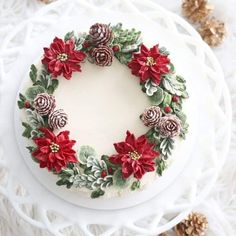 a white cake decorated with poinsettis and pine cones