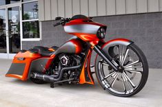 an orange and black motorcycle parked in front of a building