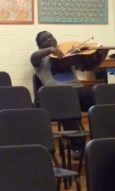 a young man playing the violin in a classroom