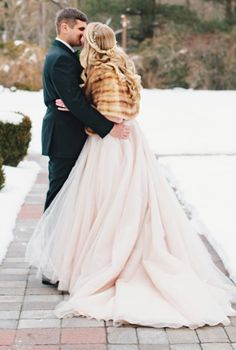 a bride and groom embracing in the snow