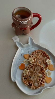 a white plate topped with waffles next to a cup of tea