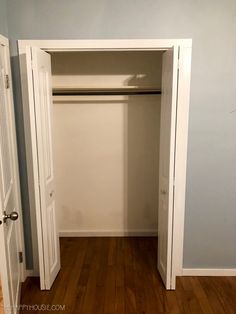 an empty closet with white doors and wood flooring in the room that is painted light blue