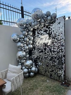 an outdoor area with balloons, chairs and a wall that says happy birthday on it