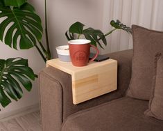 a coffee cup sitting on top of a wooden table next to a plant in a living room