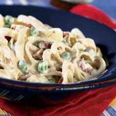 a bowl filled with pasta and peas on top of a red cloth next to a fork