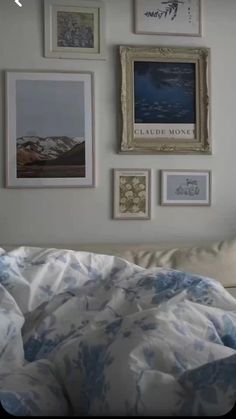 a bed with blue and white comforter next to pictures on the wall