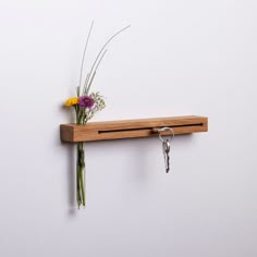 a wooden shelf with flowers and keys hanging from it's hooks on the wall