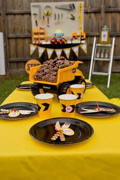 a yellow table topped with black plates covered in desserts and candy bar wrappers