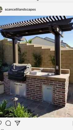 an outdoor kitchen with grill and sink under a pergolated roof